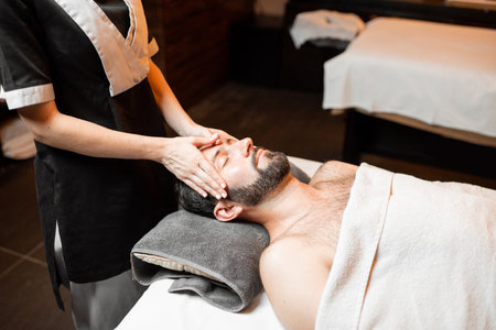 Bearded man receiving a facial massage, relaxing at Spa salon, close-upの写真素材