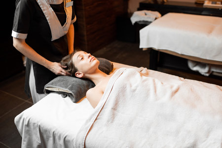 Young woman receiving a facial massage, relaxing at Spa salon