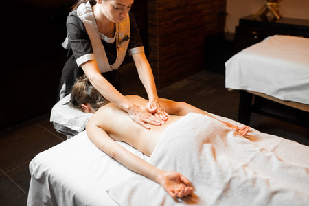 Professional female masseur doing a back massage to a young woman at Spa salonの写真素材