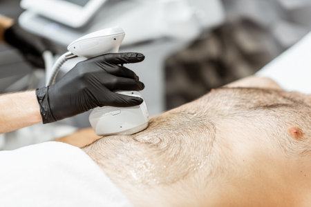 Man during an ultrasound liposuction procedure at luxury Spa salon. Doctor working on abdomen area,...