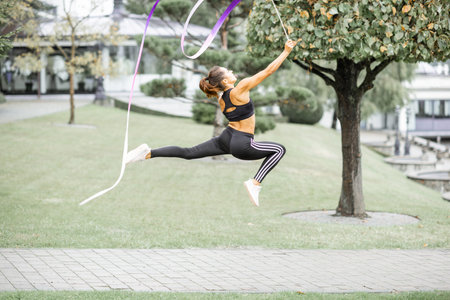 Athletic woman practising rhythmic gymnastics with a ribbon outdoorsの写真素材
