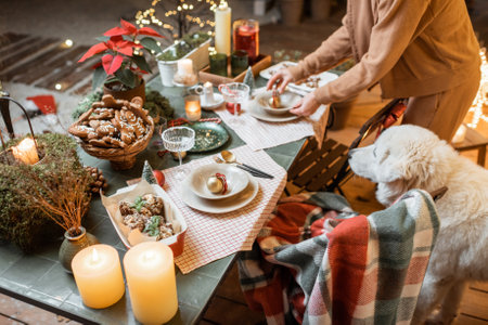 Woman serving and decorating a festive dinner table on the christmas eve outdoors on the terraceの写真素材