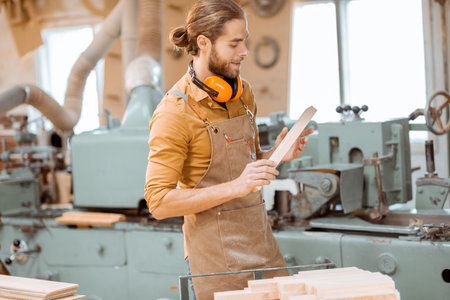 A carpenter works on a woodworking machine, holding cutter at the workshopの写真素材