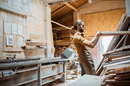 Carpenter or warehouse worker choosing raw wood material for the work at the carpentry storage