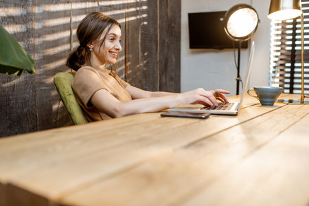 Happy woman dressed in domestic suit working on the laptop from cozy home officeの写真素材