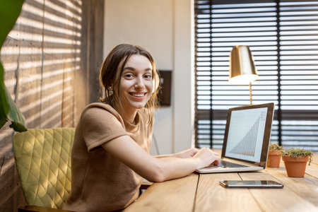 Young woman in domestic suit working on laptop at the cozy home office. Concept of work from homeの写真素材