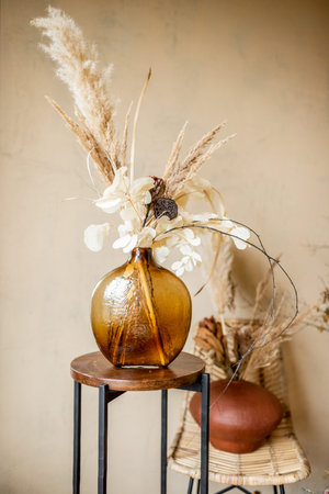 Composition of dried flowers and herbs in vases on a beige wall background