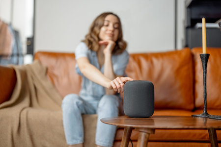 Woman touching black audio assistant column on the coffee tableの写真素材