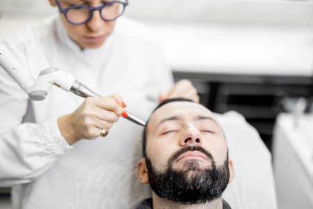 Cosmetologist doing laser facelifting procedure in beauty clinicの写真素材