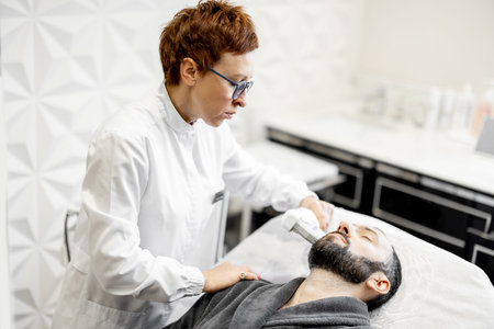 Man on ultrasound face lifting procedure in cosmetology salon