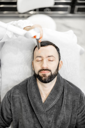 Cosmetologist doing laser facelifting procedure in beauty clinic