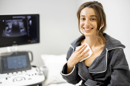 Woman after examining thyroid of female patient with ultrasound scan in clinicの写真素材