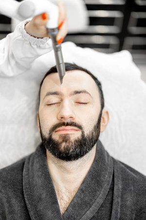 Cosmetologist doing laser facelifting procedure in beauty clinic