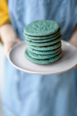 A stack of blue pancakes in woman hands.の写真素材