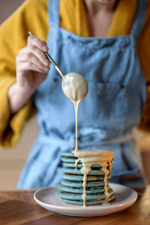 Woman pouring blue pancakes with caramel souse.の写真素材