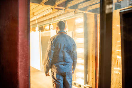 Painter in protective wear paints metal products with powder paint. Powder coating process at the manufacturing. High quality photoの写真素材