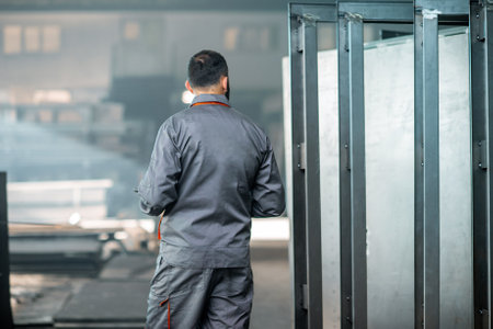 Painter in protective wear paints metal products with powder paint. Powder coating process at the manufacturing. High quality photoの写真素材