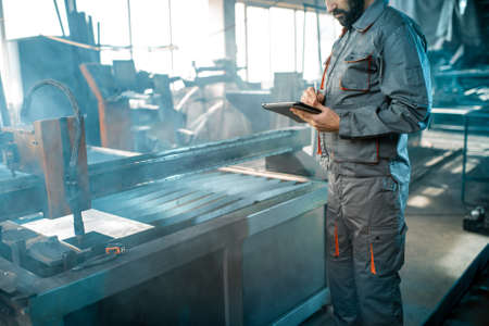 Painter in protective wear paints metal products with powder paint. Powder coating process at the manufacturing. High quality photoの写真素材