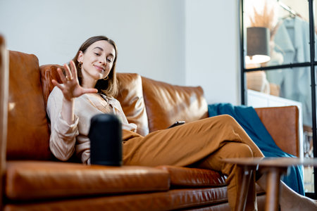 Woman speaking with audio assistant column on sofa