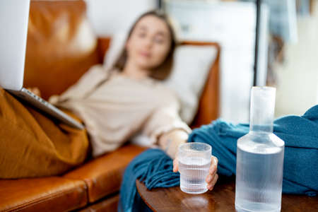 Woman working on laptop and lying on sofaの写真素材