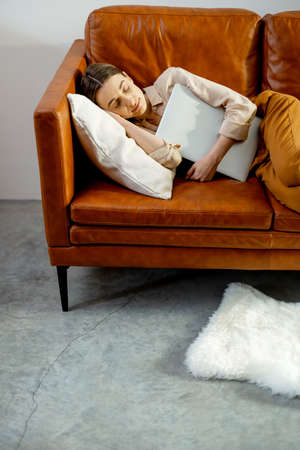 Woman fell asleep on the comfortable brown couch.の写真素材