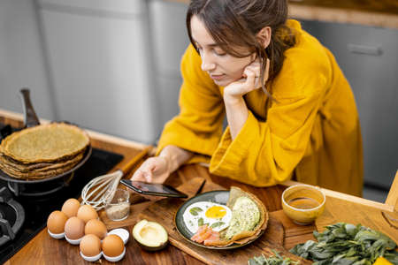 Woman enjoys breakfast on the kitchen in the morningの写真素材