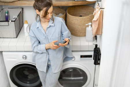 Woman with phone in the laundry roomの写真素材