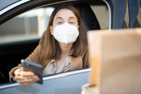 Woman driving car with protective mask on her face.