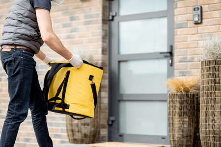 Courier wearing mask and gloves holds a parcel boxの写真素材
