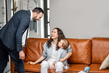 Young mom sitting with newborn son on sofa.の写真素材