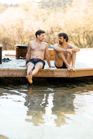 Company of male friends sitting on the terrace and wetting their feetの写真素材