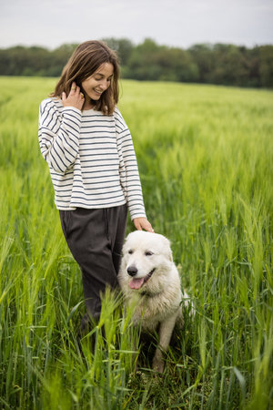 Relaxed woman standing in green field and enjoys calm nature