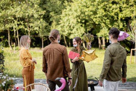 Young adult friends gathering for birthday party on nature. Happy to greet and embrace each other after the pandemicの写真素材
