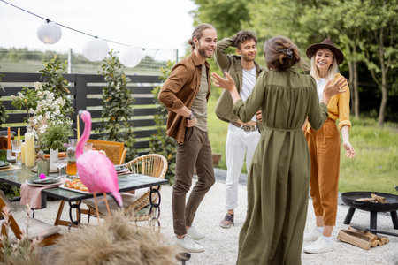 Young adult friends hang out, talking and having fun together at the beautiful backyard of the country house. Resting outdoors and meeting friends offline in natureの写真素材
