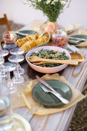 Beautifully served wooden table in natural boho style outdoors. Dining table decorated with field flowers, dishes and fresh foodの写真素材