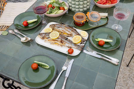 Grilled trout fish on a beautifully served green table outdoors, view from aboveの写真素材