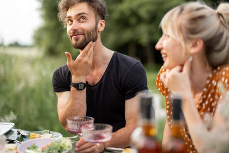 Pretty couple have fun, talking and drinking wine at lunch outdoors. Young people spending summer time dining outdoorsの写真素材