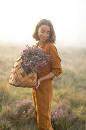 Portrait of a cute woman with a freshly picked up heather bouquet in the mountains in a foggy weatherの写真素材
