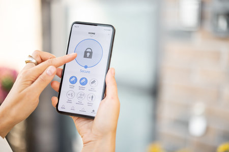 Woman closes the door or turns on the house alarm with a mobile phone. Device with running program...