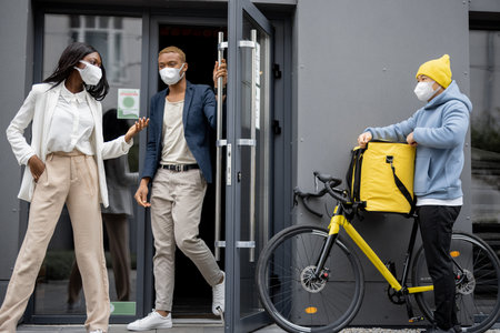 Courier with order waiting business people who coming out office building. Concept of shipping and...