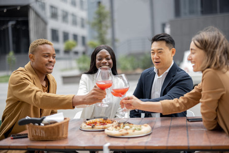 Multiracial business team toasting with wine while celebrating at outdoor cafe. Concept of...