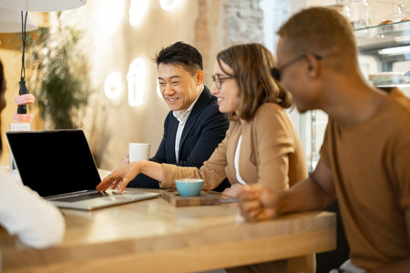 Multiracial business team watching something on laptop while working in cafe or restaurant. Concept...