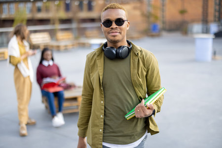 Smiling black student guy on background of her female friends outdoors. Concept of education and...