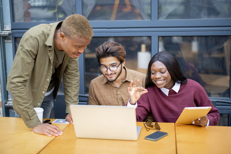 Multiracial students having video call on laptop at table outdoors. Concept of remote and...