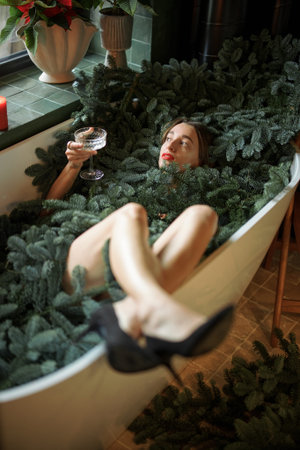 Naked woman lying in the bathtub full of nobilis branches. Concept of celebrating New Year holidays....