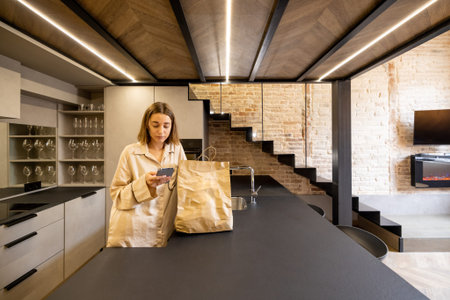 Woman unpacking shopping bags with fresh groceries at modern kitchen. Concept of healthy eating,...