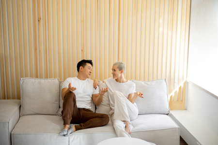 Multiracial couple sit and rest on sofa at home. Concept of relationship and spend time together....