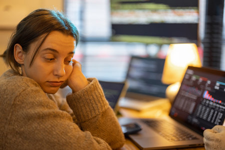 Portrait of tired overworked woman sitting at workplace with computers. Female programmer writing...