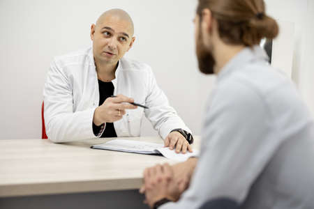 Physical therapist talking to male patient during medical appoitment at the officeの写真素材