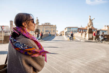 Young stylish woman walking near Holy Trinity bridge in Florence city, visiting famous italian landmarks. Idea of italian style and travelの写真素材